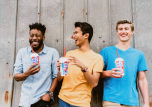 Three men smiling drinking an ICEE