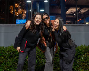 Joann Mercado Hicks (far right) posing with two smiling colleagues outside a nighttime venue.