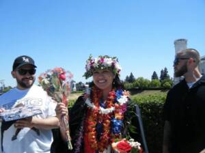 Jordan beaming with floral leis after a ceremony, showcasing the joy of beginnings and her creative vision for video production success at Windsong Productions.