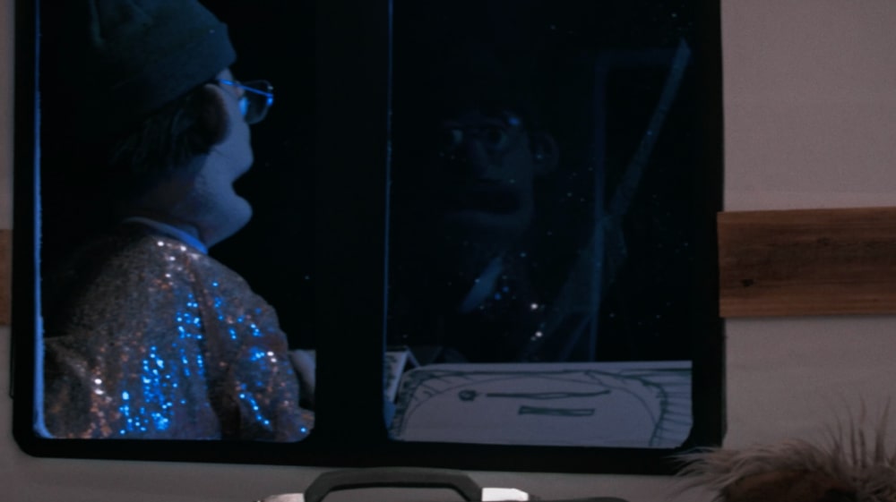 Puppet characters seen through a van window at night, wearing sparkly costumes in a whimsical recreation of a Home Alone travel scene