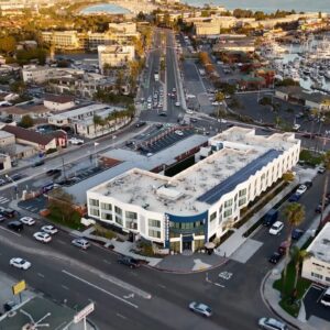 Aerial view of Hilton Monseraz San Diego, a modern boutique hotel with solar panels, located near a coastal marina with cityscape surroundings.