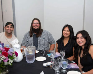 ordan Singh seated with Windsong Productions teammates at their table, celebrating her Rising Star Award win.