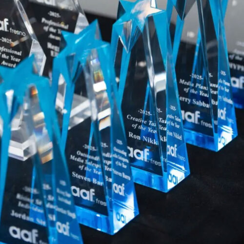 Row of 2025 AAF Fresno crystal and blue star-shaped trophies lined up on a black table.